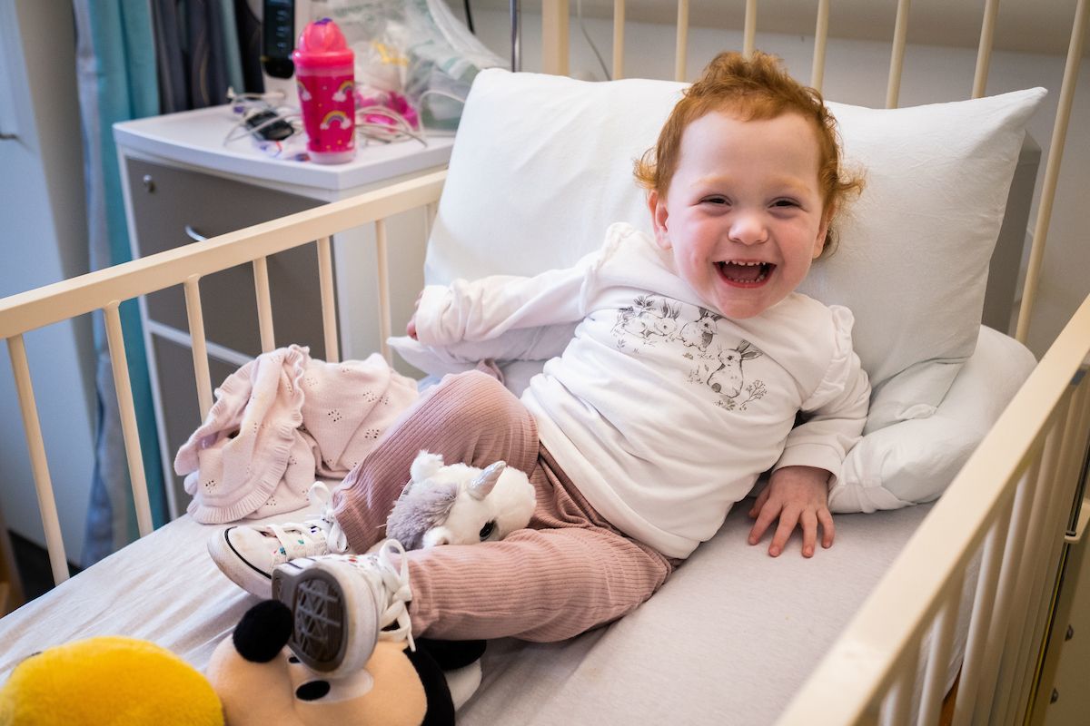 Edinburgh Children's Hospital Charity. Red haired toddler laughs in a hospital bed.